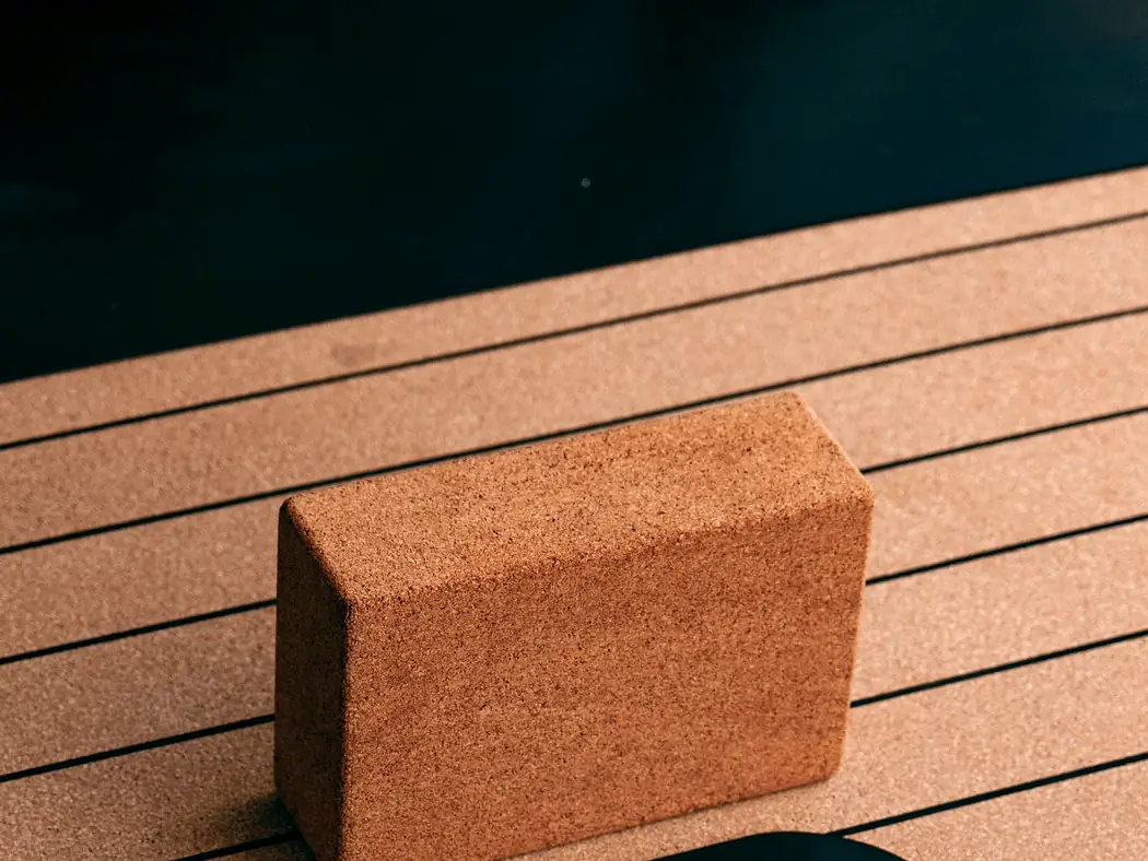 A cork yoga block resting on a cork and rubber mat.